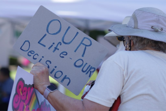 Elderly woman at a pro-choice rally holding an "Our Life - Our Decision" sign